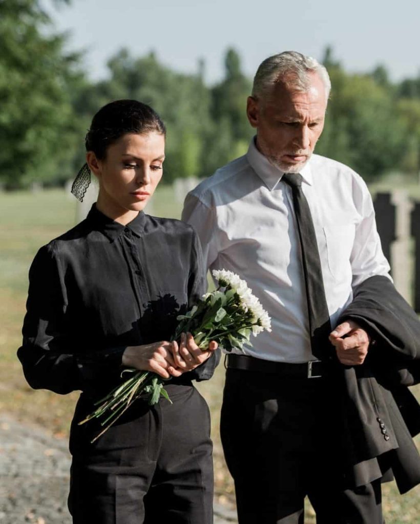 bearded-senior-man-walking-near-woman-with-flowers-on-funeral-e1636904705190.jpg